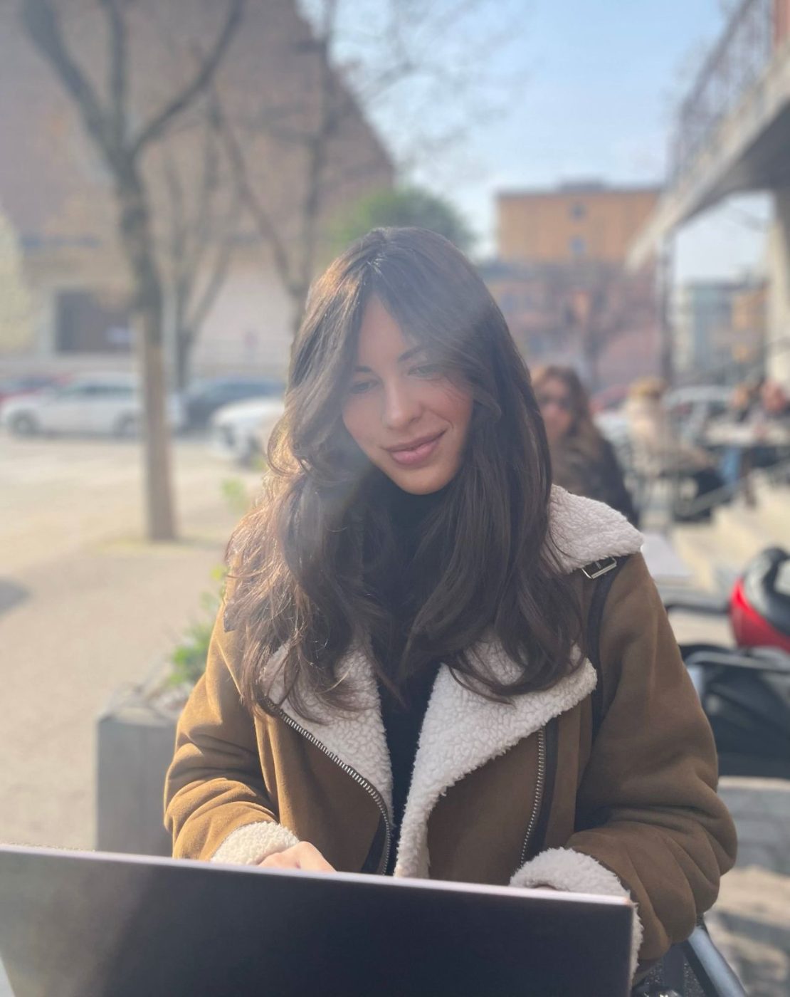 Caterina, founder of La Proposta, working at a cafe table on a sunlit Verona street